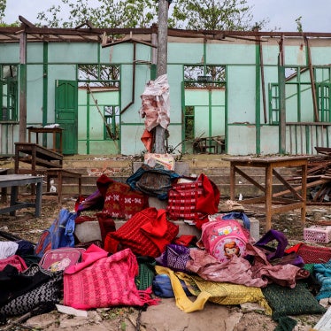 A pile of backpacks in front of a damaged school building.