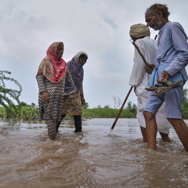 Villagers wade through a flooded area.