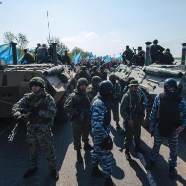 Army and police officers block the road ahead of a protest by Crimean Tatars (visible in the background) at a Russia-Ukraine border checkpoint outside the town of Armyansk, Crimea on May 3, 2014.