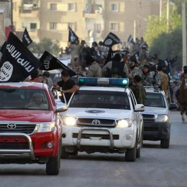 Militant Islamist fighters waving flags, travel in vehicles as they take part in a military parade along the streets of Syria's northern Raqqa province, June 30, 2014. 