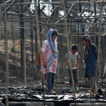 Migrants stand among the remains of a burned tent at the Moria hotspot, after a fire ripped through tents and destroyed containers on the island of Lesbos, Greece, September 20, 2016.