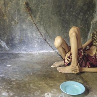 A woman chained in a room built behind her family home in Ponorogo, East Java. She is forced to eat, sleep, and defecate in this room.