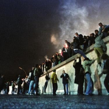 East German citizens climb the Berlin Wall at the Brandenburg Gate after the opening of the border was announced early on November 9, 1989. 