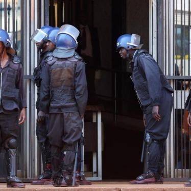 Riot police stand guard as opposition party supporters, arrested following Friday's protest march, arrive at court in Harare, Zimbabwe