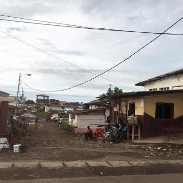 A wide shot of houses in a neighborhood of Malabo, Equatorial Guinea, with unpaved roads, one-storey houses, and trash 