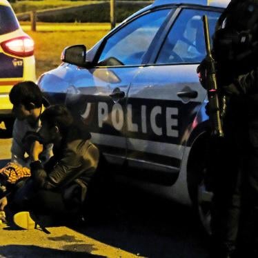 French police detain two migrants, one a 14-year-old boy, before dispersing a late-night food distribution in Calais on June 29, 2017. 