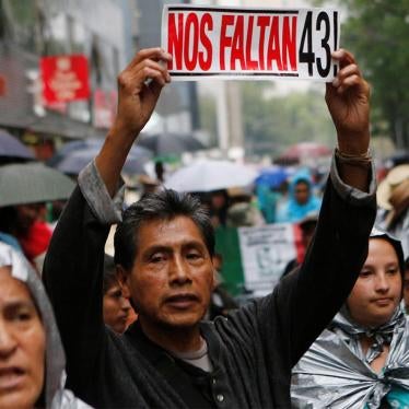 A protester holds up a sign – "We are missing 43!" – with relatives of the 43 missing students from a teacher’s college in Ayotzinapa during a march in Mexico City. © 2016  Henry Romero/Reuters