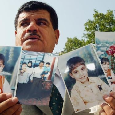 داود موسى، والد بهاء موسى الذي توفي في 2003 في عمر 26 عاما رهن الاحتجاز من قبل جنود بريطانيين في العراق، رافعا صور ابنه وصورة عائلية أمام وسائل الإعلام، بعدما وصوله إلى جلسة بمحكمة بريطانية في 28 يوليو/تموز 2004 حول انتهاكات حقوق الإنسان في العراق. © 2004