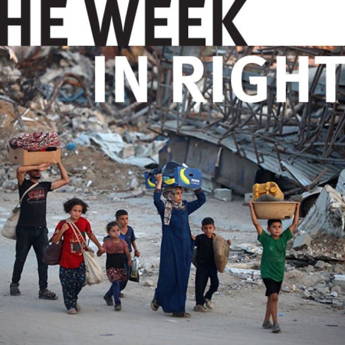 A group of people carry their belongings as they walk. 