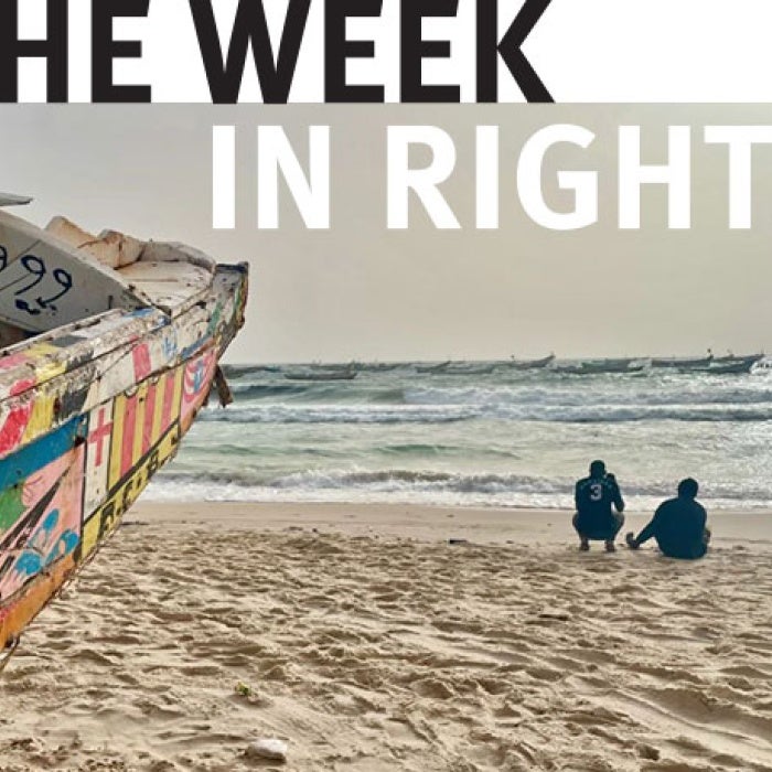 Two figures walk on beach. 