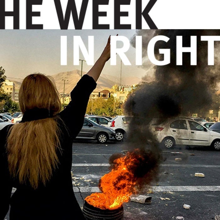 Figure holds up fist in front of fire. 